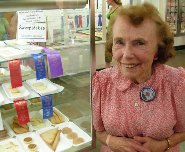 >Marjorie Johnson posing alongside ribbon winning baked goods at the Minneosta State Fair.